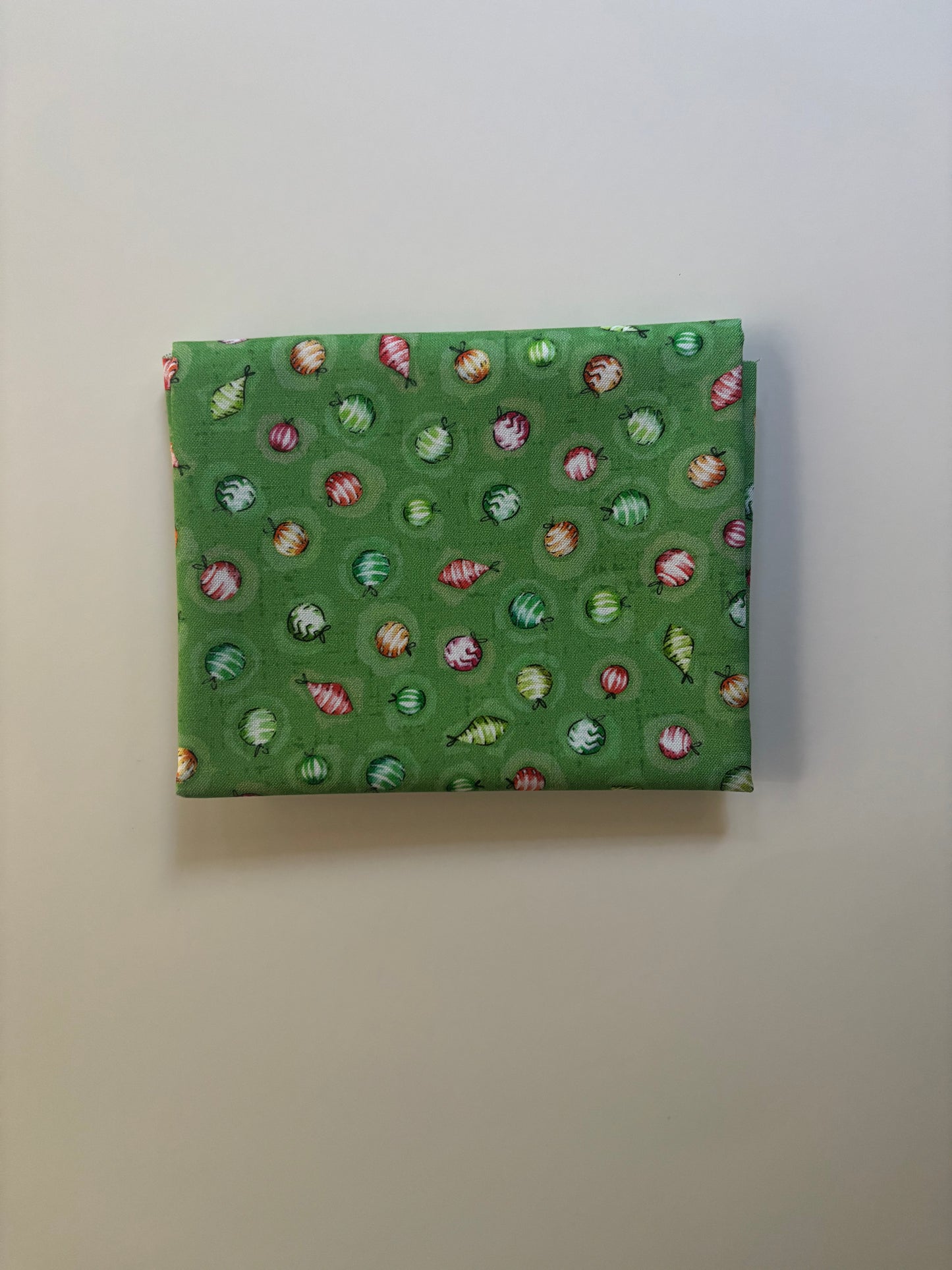 Green fabric with a pattern of small colorful shapes on a plain background