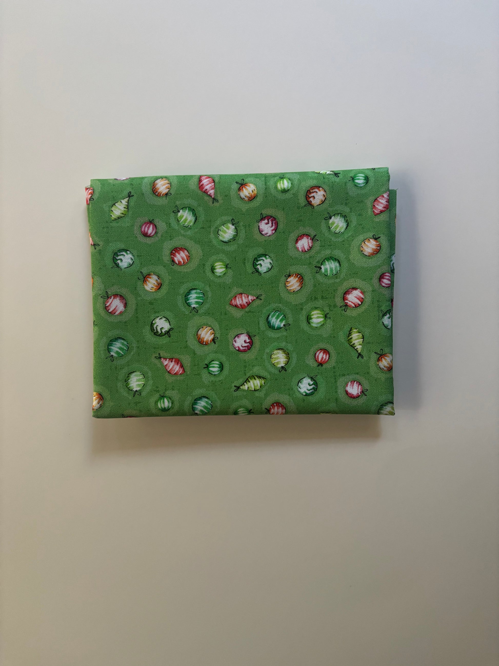 Green fabric with a pattern of small colorful shapes on a plain background